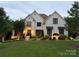 Beautiful white brick home with manicured lawn, professional landscaping, and decorative black window awnings at 9604 Oliver Ct, Harrisburg, NC 28075