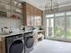 Bright laundry room showcasing custom cabinets, sleek appliances, brick backsplash, and a large window with a scenic view at 9604 Oliver Ct, Harrisburg, NC 28075