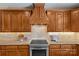 Close up of kitchen with granite countertops, tiled backsplash, stainless steel stove, and wood cabinetry at 1019 Westlake Dr, Kannapolis, NC 28081