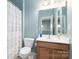 Bright bathroom features modern fixtures, a vanity, toilet and shower with white curtain at 1027 Writers Way, Cornelius, NC 28031