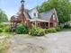 Lovely brick home with an upstairs deck and a cozy front porch, surrounded by lush landscaping at 1102 Lane St, Kannapolis, NC 28083