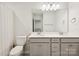 Bright bathroom features dual sinks, gray cabinets, quartz countertop, and modern fixtures at 13323 Savaine St, Charlotte, NC 28278