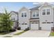 Townhouse exterior with light gray siding, stone accents and white garage doors at 13323 Savaine St, Charlotte, NC 28278