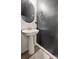 Stylish powder room with a pedestal sink, modern mirror, and sleek, dark accent wall at 13323 Savaine St, Charlotte, NC 28278