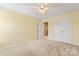 Neutral carpeted bedroom featuring double door closet with a ceiling fan and adjacent doorway at 13733 Castleford Dr, Mint Hill, NC 28227
