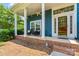 Inviting covered front porch with seating area and charming brick accents at 13733 Castleford Dr, Mint Hill, NC 28227