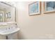Elegant powder room featuring a pedestal sink, decorative mirror, and neutral walls at 13733 Castleford Dr, Mint Hill, NC 28227