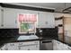 A kitchen sink and a stainless steel dishwasher complement white cabinets and black countertops at 1553 Home Trl # 51, Lincolnton, NC 28092