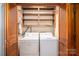 A laundry closet with wooden shelves and a full-sized washer and dryer at 1553 Home Trl # 51, Lincolnton, NC 28092