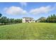 Expansive backyard view of a large white brick home with a well-manicured lawn and trees at 200 Squash Harvest Ct, Matthews, NC 28104