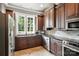 Well-lit kitchen features brown cabinets, stainless steel appliances, and black countertops at 2377 Maple Grove Nw Ln, Concord, NC 28027