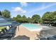 Community pool with lounge chairs and umbrellas surrounded by trees at 2377 Maple Grove Nw Ln, Concord, NC 28027