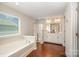 Bright bathroom with hardwood floors, dual sinks, a soaking tub, and a glass enclosed shower at 3816 Ernie Dr, Charlotte, NC 28269