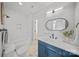 Modern bathroom features a combo tub/shower, oval mirror, and vanity with blue cabinets at 4349 Castleton Rd, Charlotte, NC 28211