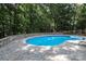 A close-up shot of the kidney-shaped pool surrounded by a paver patio and lush greenery at 5051 Carillon Way, Charlotte, NC 28270