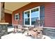 Cozy rocking chairs on a charming front porch with stone accents and large windows at 670 Cricket Ln, Mt Ulla, NC 28125