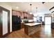 Well-lit kitchen boasts granite counters, a stone-clad island, wood floors, and stainless steel appliances at 670 Cricket Ln, Mt Ulla, NC 28125