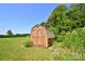 Rustic backyard storage shed on a well-maintained green lawn, surrounded by mature trees at 670 Cricket Ln, Mt Ulla, NC 28125