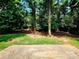 Expansive backyard with mature trees, a concrete patio, and ample green space at 7228 Rollingridge Dr, Charlotte, NC 28211