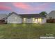 Backyard at sunset with clear vinyl siding and patio area with sliding glass doors at 7616 Shiny Meadow Ln, Charlotte, NC 28215