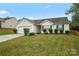 Single-story home with a two-car garage, a concrete driveway, and a green, landscaped lawn at 7616 Shiny Meadow Ln, Charlotte, NC 28215
