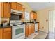 Bright kitchen with wooden cabinets and white appliances, with a small window over the sink at 7616 Shiny Meadow Ln, Charlotte, NC 28215