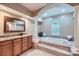 A spacious bathroom with granite counters, wood cabinets, soaking tub, and arched doorway with tiled flooring at 844 Clonmel Dr, Matthews, NC 28104