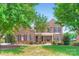 Traditional brick home with manicured front lawn and mature trees, featuring a covered front porch at 844 Clonmel Dr, Matthews, NC 28104