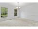 An empty dining room with carpet, chair rail, and large windows overlooking greenery at 9833 White Cascade Dr, Charlotte, NC 28269