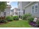 A private backyard with green grass, lush plants, a white pergola, and nearby homes at 10818 Alvarado Way, Charlotte, NC 28277
