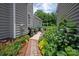 Landscaped side yard leads to a patio with grill and lush flowerbeds at 10818 Alvarado Way, Charlotte, NC 28277