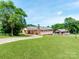Spacious brick home with large grassy backyard, mature trees, and long driveway at 1606 N Rhyne St, Gastonia, NC 28054