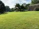 Expansive backyard with lush green grass and a few mature trees with the brick house in the background at 3009 Grier St, Newton, NC 28658