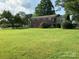 Spacious backyard with a deck attached to a traditional brick home, surrounded by mature trees and greenery at 3009 Grier St, Newton, NC 28658
