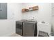 Well-lit laundry room with gray washer/dryer, utility sink, and shelving for organized storage at 3899 Zemosa Nw Ln, Concord, NC 28027