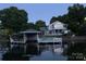 A two-story home with waterfront access, a boat dock, a covered patio and calm water reflections at dusk at 47209 Paradise Ln, Norwood, NC 28128