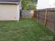 Backyard view of yard, home siding, and a wooden fence with access gate at 569 River View Dr, Lowell, NC 28098