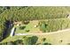 Expansive aerial view of a property featuring a mobile home, storage buildings, and bordered by lush woodland and a dirt drive at 589 Owls Den Rd, Lincolnton, NC 28092