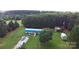Expansive property featuring a blue home, multiple outbuildings, lush greenery, and parking area at 589 Owls Den Rd, Lincolnton, NC 28092