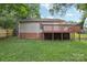 View of the home's backyard featuring a brown deck, vinyl siding, and mature trees at 603 Paradise St, Monroe, NC 28112