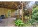 View of the brick house backyard with a small tiled patio, wooden staircase, and garden at 6632 Candlewood Dr, Charlotte, NC 28210