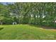 Large backyard with lush green grass and a storage shed surrounded by mature trees at 1008 Dumbarton Rd, Gastonia, NC 28054