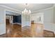 Open dining room with hardwood floors, chandelier, and view into other living spaces at 1008 Dumbarton Rd, Gastonia, NC 28054