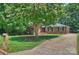 Well-maintained brick home with lush green lawn and mature trees along the driveway at 1008 Dumbarton Rd, Gastonia, NC 28054