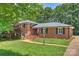 Charming brick home with a well-manicured lawn, black shutters, and mature trees at 1008 Dumbarton Rd, Gastonia, NC 28054