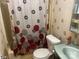 Compact bathroom featuring a shower-tub combo, toilet, and vanity with coordinated floral-themed decor at 1064 Calico Farm Ct, Cleveland, NC 27013