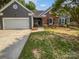 Charming home with a gray exterior, brick accents, a well-manicured lawn, and an attached two-car garage at 11103 Fox Cove Dr, Charlotte, NC 28273