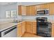 Kitchen featuring wooden cabinetry and black appliances, with a stainless steel dishwasher at 157 Talbert Town Loop, Mooresville, NC 28117
