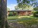 Cozy brick home featuring a spacious backyard with a wooden deck, lawn, and mature trees at 331 Elwood St, Kannapolis, NC 28081
