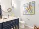 Stylish powder room showcasing a blue vanity, a round mirror, and a vibrant floral painting at 342 Battery Cir, Clover, SC 29710